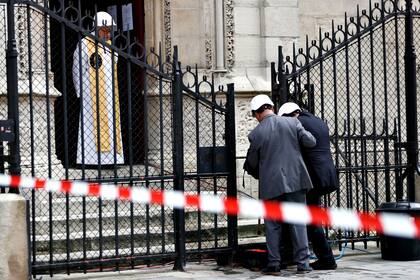 El rector de la catedral de Notre Dame, Patrick Chauvet saluda a las personas que llegan a la primera misa de la catedral de París dos meses después del incendio
