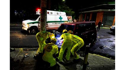 Los rescatadores intentan desconectar una batería de automóvil para evitar el riesgo de incendio después de un accidente automovilístico en San Salvador