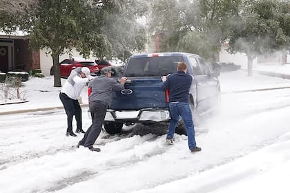 Los residentes ayudan a un conductor a salir del hielo en la carretera en Round Rock, Texas, el 17 de febrero de 2021, después del paso de una tormenta de invierno