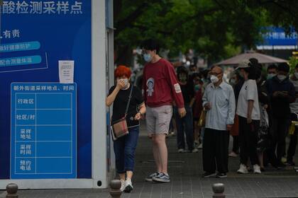 Los residentes hacen fila para hacerse un frotis de garganta en un centro de pruebas de coronavirus en Pekín, el jueves 9 de junio de 2022. Miles de cabinas de prueba de COVID-19 han aparecido en las aceras de todo en la capital y varias otras ciudades chinas en el último giro en el país de la estrategia cero-Covid. (AP Photo/Andy Wong)
