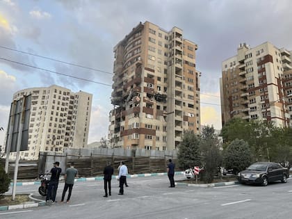 Los residentes observan un apartamento dañado en Teherán, Irán, la madrugada del viernes 13 de junio de 2025
