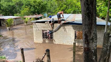 Los residentes reparan el techo de su casa inundada después de que un río se creciera debido a las fuertes lluvias tras el paso del huracán Beryl en la carretera de Cumaná a Cumanacoa, estado Sucre, Venezuela, el 2 de julio de 2024