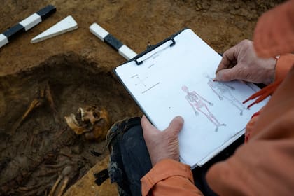 Un investigador realiza un croquis del esqueleto del soldado soviético que fue hallado en un campo, en Alemania