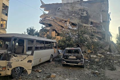 Los restos de vehículos destruidos yacen en el lugar de un ataque aéreo israelí nocturno que tuvo como objetivo un barrio de la ciudad costera sureña de Tiro