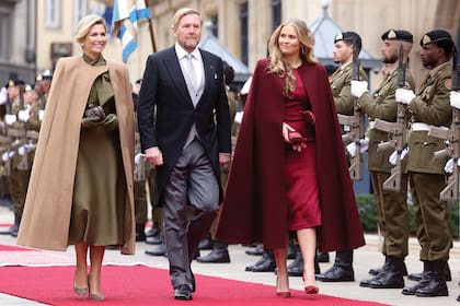 Los reyes de Países Bajos y la princesa heredera participaron de todos los actos del viernes 3. Por la mañana, fueron testigos de la ceremonia de entronización del nuevo Gran Duque, evento en el que Máxima y Amalia dieron cátedra de estilo: la Reina con un diseño midi en verde oliva, con la cintura marcada y un gran lazo al cuello, que combinó con la capa perfecta en color camel, todo de Claes Iversen, y accesorizó con guantes de cuero, clutch Bottega Veneta y stilettos Gianvito Rossi. Su hija con un vestido de Alex Perry, que también completó con capa al tono de Valentino (préstamo de su madre), guantes de cuero y zapatos Gianvito Rossi