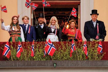 Los reyes Harald y Sonia, los príncipes herederos Haakon y MetteMarit, y los príncipes Sverre Magnus e Ingrid Alexandra, ondean banderas noruegas desde el balcón del Palacio Real durante las celebraciones por el Día de la Constitución, el 17 de mayo de 2021.