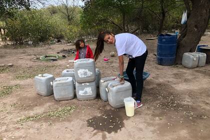 Camila prepara la leche con agua que saca de los bidones para darle de comer a los chanchos
