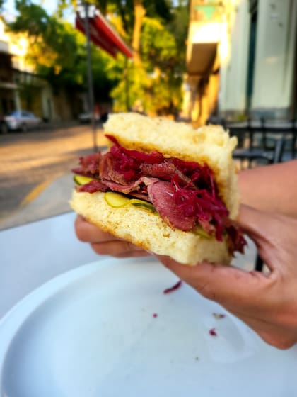 Los sándwiches de Isla Flotante se destacan por lo generosos, como este con pastrón, repollo colorado, mostaza francesa y pepinos. 