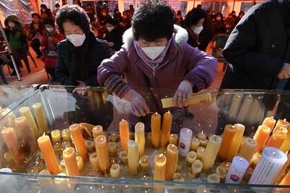 Los seguidores budistas colocan velas durante un servicio de adoración para los estudiantes que realizan el examen anual de capacidad académica universitaria, en el templo Jogye en Seúl el 3 de diciembre de 2020