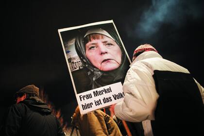 Los simpatizantes de Pegida marchan por Dresde portando banderas alemanas o regionales y tienen a Angela Merkel como blanco de sus críticas