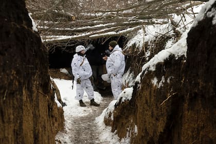 Los soldados ucranianos se refugian en una trinchera en la primera línea de batalla mientras sus compañeros disparan un mortero de 120 mm hacia las posiciones rusas, en la región de Bahkmut.