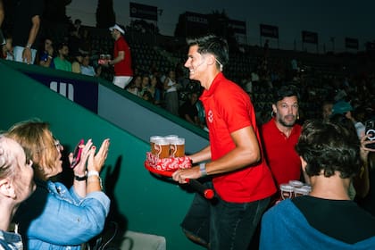 Los tenistas repartiendo Stella en la tribuna.