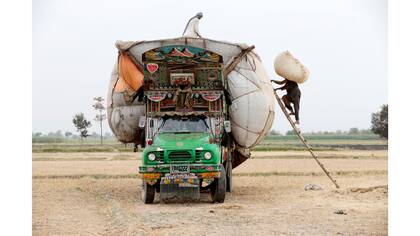 Los trabajadores cargan paja en un camión decorado fuera de Faisalabad