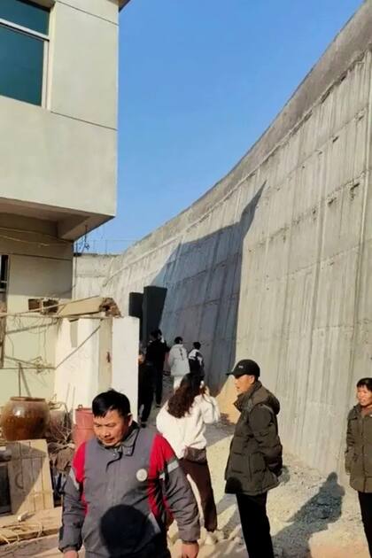 Los trabajadores de la autopista junto al inmenso muro de concreto que separa la casa de Huang de la obra