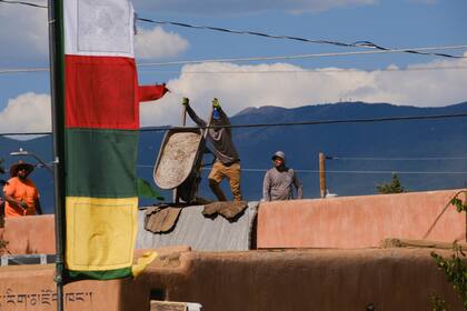 Los trabajadores de la construcción llevan camisas contra el sol mientras trabajan en un techo en Santa Fe, Nuevo México, el lunes 17 de julio de 2023.