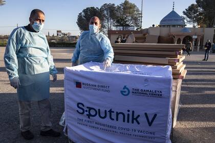 Los trabajadores de la salud descargan cajas con dosis de la vacuna rusa Sputnik V, provenientes de los Emiratos Árabes Unidos, a su llegada a la Franja de Gaza a través del cruce de Rafah con Egipto, el 21 de febrero de 2021