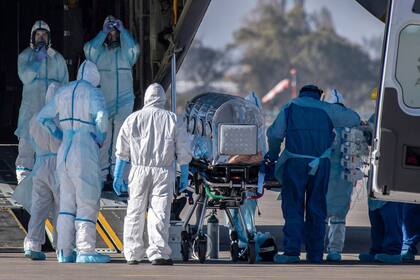 Los trabajadores de la salud trasladan a un paciente infectado con COVID-19 a un Hércules C-130, para llevarlo a la ciudad de Concepción, en una base de la Fuerza Aérea de Chile en Santiago, Chile, el 24 de mayo de 2020