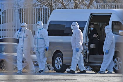 Los trabajadores de la salud usan trajes protectores como medida preventiva contra el coronavirus COVID-19 mientras esperan afuera del Centro Internacional de Exposiciones de Nueva China, cerca del Aeropuerto Capital de Beijing