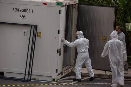 Los trabajadores de la salud usan trajes de protección cuando dejan el cuerpo de una víctima del nuevo coronavirus en un contenedor refrigerado en el Hospital Público Vinte Oito de Agosto, en Manaus, Brasil, el 4 de enero de 2021