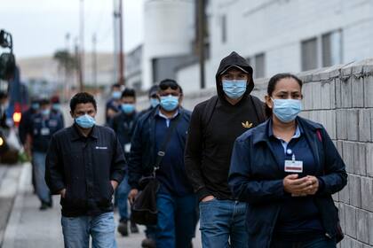 Los trabajadores de producción con máscaras llegan para su turno a la planta Hyundai en Tijuana, estado de Baja California, México, el 18 de mayo de 2020, en medio de la pandemia de coronavirus