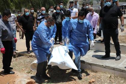 Los trabajadores de salud palestinos llevan el cuerpo de un hombre de 46 años que murió después de contraer la enfermedad Covid-19, para ser enterrado en la ciudad cisjordana de Hebrón el 5 de julio de 2020