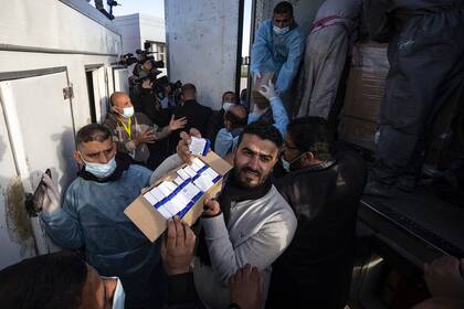 Los trabajadores descargan de un camión cajas con dosis de la vacuna rusa Sputnik V, provenientes de Emiratos Árabes Unidos, a su llegada a la Franja de Gaza a través del cruce de Rafah con Egipto, el 21 de febrero de 2021