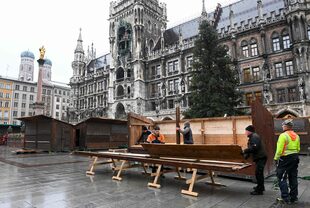 Los trabajadores desmantelan un puesto del mercado navideño en Marienplatz en el centro de Múnich, en el sur de Alemania, el 22 de noviembre