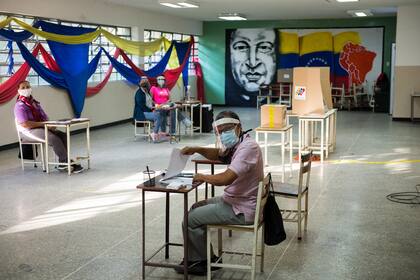 Los trabajadores electorales esperan a los votantes en una mesa de votación en una escuela en Caracas, el 6 de diciembre de 2020 durante las elecciones legislativas de Venezuela