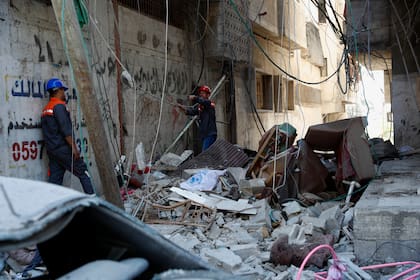 Los trabajadores inspeccionan los escombros del edificio destruido de Abu Hussein que fue alcanzado por un ataque aéreo israelí la mañana del 19 de mayo de 2021