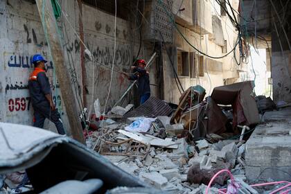 Los trabajadores inspeccionan los escombros del edificio destruido de Abu Hussein que fue alcanzado por un ataque aéreo israelí temprano en la mañana