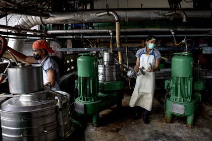 Los trabajadores se preparan para limpiar las máquinas centrífugas en la fábrica de caucho VA Latex, en la provincia de Trang, en el sur de Tailandia