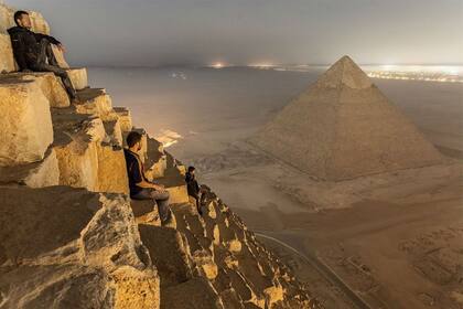 Los tres jóvenes fotógrafos rusos hacen una pausa en la cima de la pirámide de Keops para contemplar El Cairo de noche