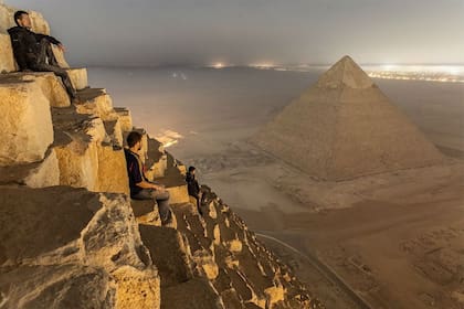Los tres jóvenes fotógrafos rusos hacen una pausa en la cima de la pirámide de Keops para contemplar El Cairo de noche