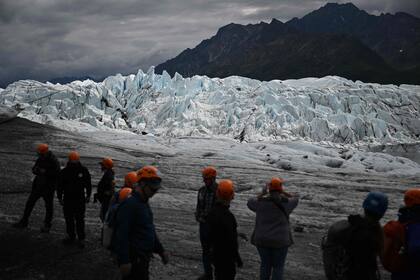 Los turistas aprecian la belleza del glaciar, que cada año retrocede y deja el fango y restos rocosos a la vista