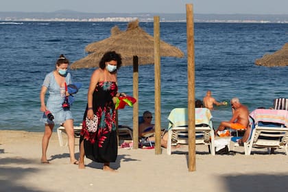Los turistas caminan en la playa de Palmanova en la isla de Mallorca el 27 de julio de 2020
