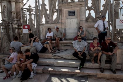 Los turistas descansan a la sombra de los pináculos y estatuas que adornan el techo del Duomo; el año pasado se recibieron 2.5 millones de visitantes