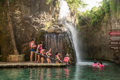 Los turistas hacen cola para entrar al estanque y nadar entre peces junto a una cascada en Xcaret.