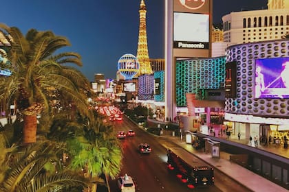 Los turistas se detienen para tomar fotografías en medio de las brillantes luces de los casinos