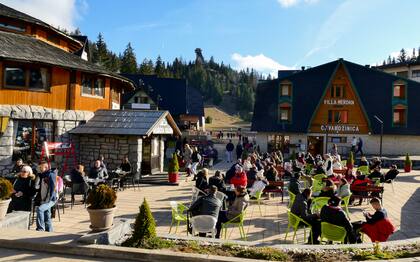 Los turistas se sientan en cafés al aire libre en un día soleado en Vlasic, una estación de esquí afectada por un clima cálido inusual en Bosnia, el martes 3 de enero de 2023. (AP Photo/Almir Alic)