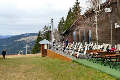 Los turistas se sientan en la terraza de un hotel en Vlasic, una estación de esquí afectada por un clima inusualmente cálido en Bosnia. (AP Photo/Almir Alic)