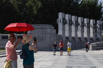 Los turistas utilizan un paraguas para protegerse del sol mientras visitan el Memorial de la Segunda Guerra Mundial el 20 de julio de 2022 en Washington, DC. 