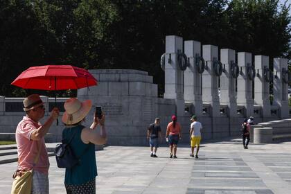 Los turistas utilizan un paraguas para protegerse del sol mientras visitan el Memorial de la Segunda Guerra Mundial el 20 de julio de 2022 en Washington, DC.