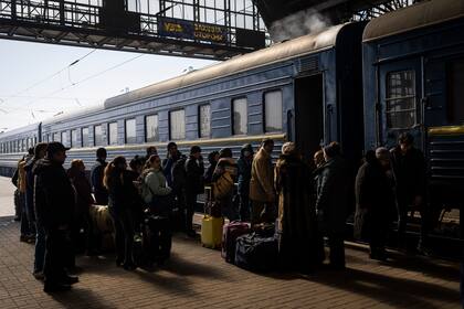 Los ucranianos que escapan de la ciudad sitiada de Mariupol junto con otros pasajeros de Zaporizhzhia se reúnen en el andén de una estación de tren tras llegar a Lviv, en el oeste de Ucrania, el domingo 20 de marzo de 2022. 