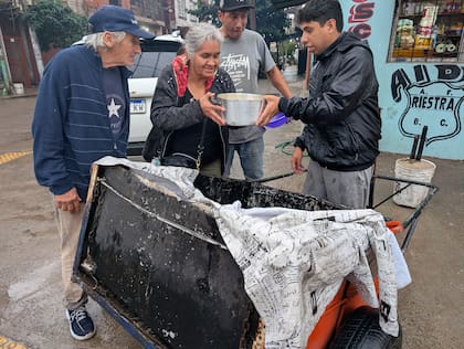 Los vecinos ya conocen a Natanael y se acercan a charlar con él mientras les sirve un plato de comida