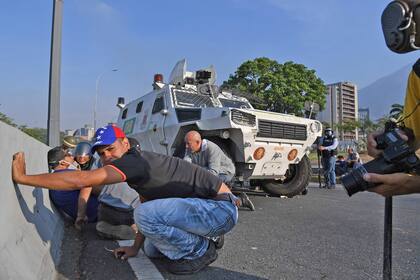 Los venezolanos se protegen durante los enfrentamientos con las fuerzas de seguridad en Caracas