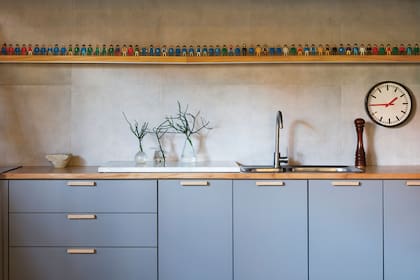 Los ventanales al patio se reservaron para el living. A la cocina, le dieron excelente iluminación artificial, y la aligeraron con este celeste grisáceo y madera clara.