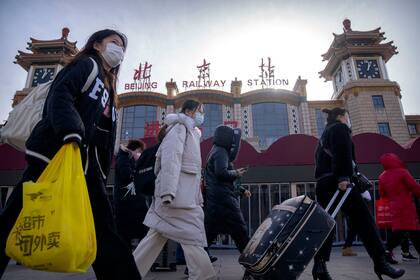 Los viajeros con máscaras faciales pasan frente a la entrada de la estación de tren de Beijing
