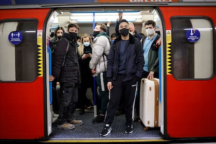 Los viajeros que usan barbijo para combatir la propagación del coronavirus, esperan a que las puertas de un subte se cierren durante la hora pico en la línea Victoria del metro de Londres el 18 de marzo de 2021
