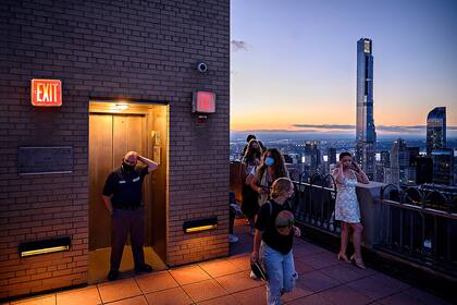 Los visitantes llegan a un mirador del Rockerfeller Center para ver cómo los edificios del horizonte de la ciudad de Manhattan se iluminan en azul y oro durante la celebración