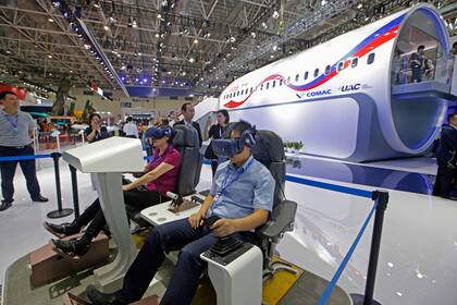 Los visitantes prueban los dispositivos de realidad virtual, junto a una maqueta a tamaño real del avión CR929 durante la 12ª Exposición Internacional Aeronáutica y Aeroespacial de China